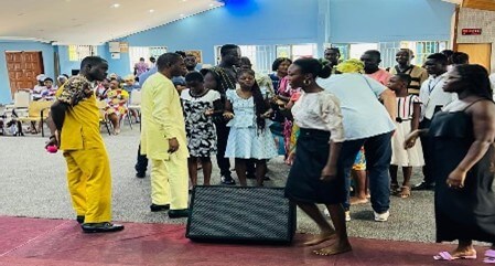 A group of people gathered indoors, engaging in conversations and activities during a mission trip event.