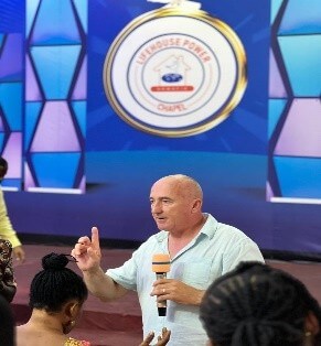 Mal addressing a congregation during a mission event at Lighthouse Power Chapel in Ghana.